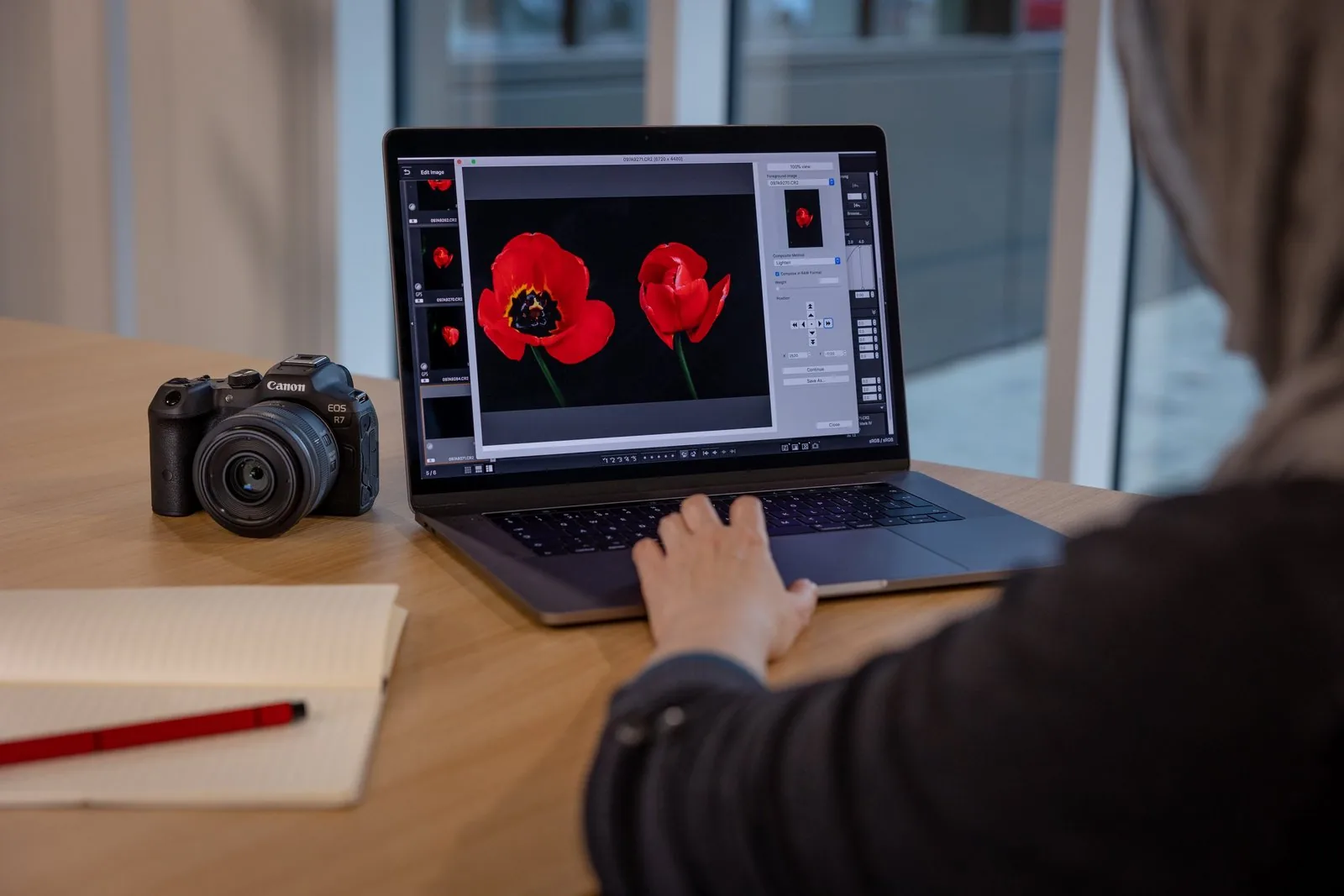 คนใช้โปรแกรม Digital Photo Professional บนโน้ตบุ๊ก มีกล้อง Canon วางอยู่ข้างกัน