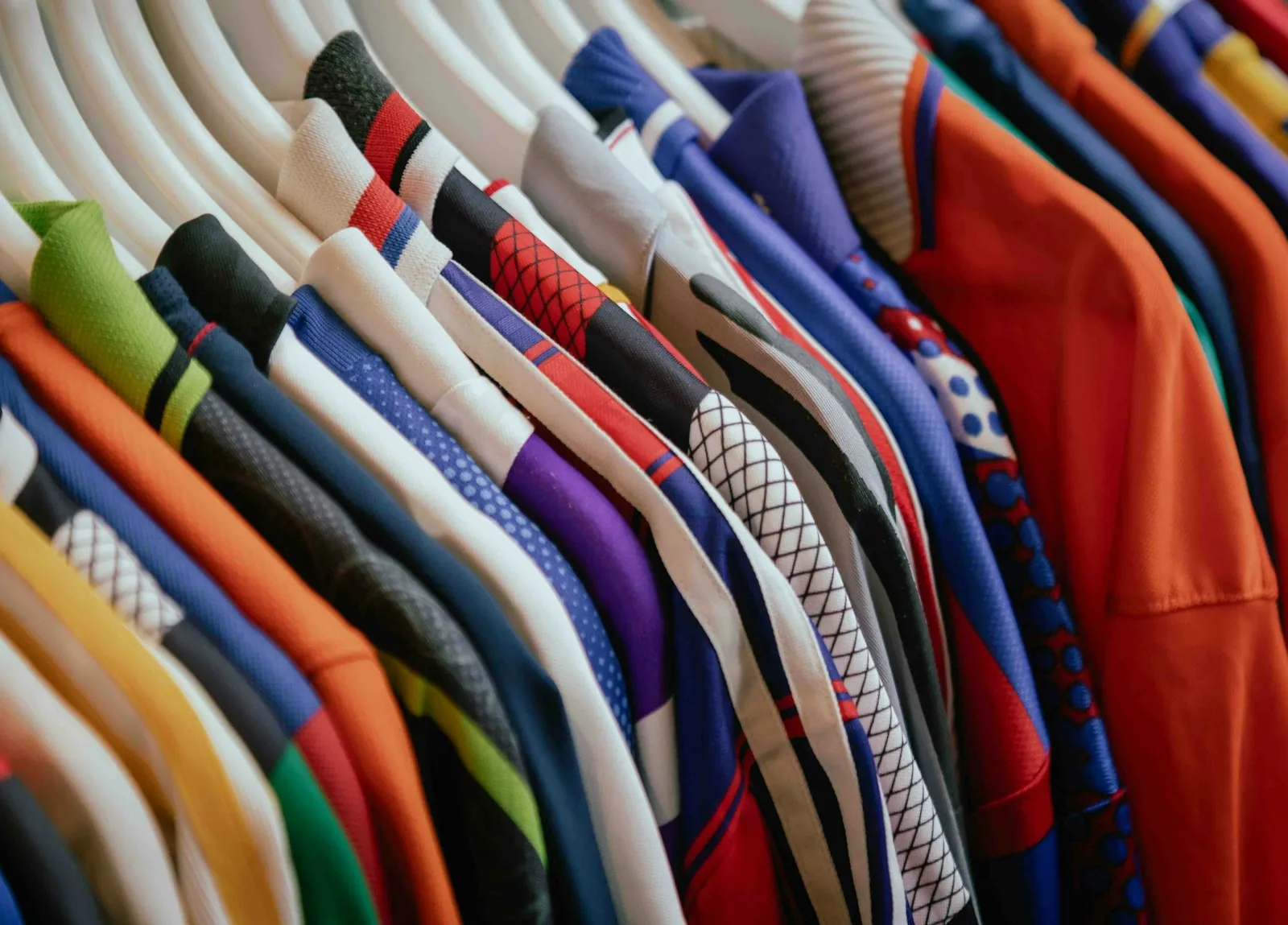 ราวเสื้อหลายสีหลายลายแขวนบนไม้แขวนสีขาว