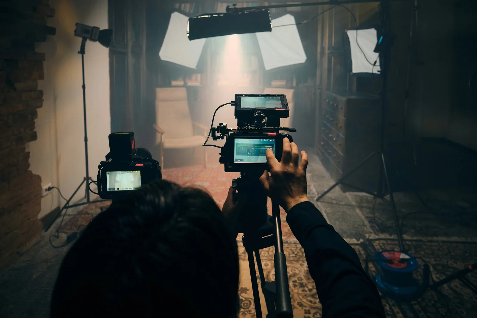 ช่างภาพถ่ายฉากในห้องที่ตั้งไฟซอฟต์บ็อกซ์หลายดวงพร้อมกล้องสองตัว