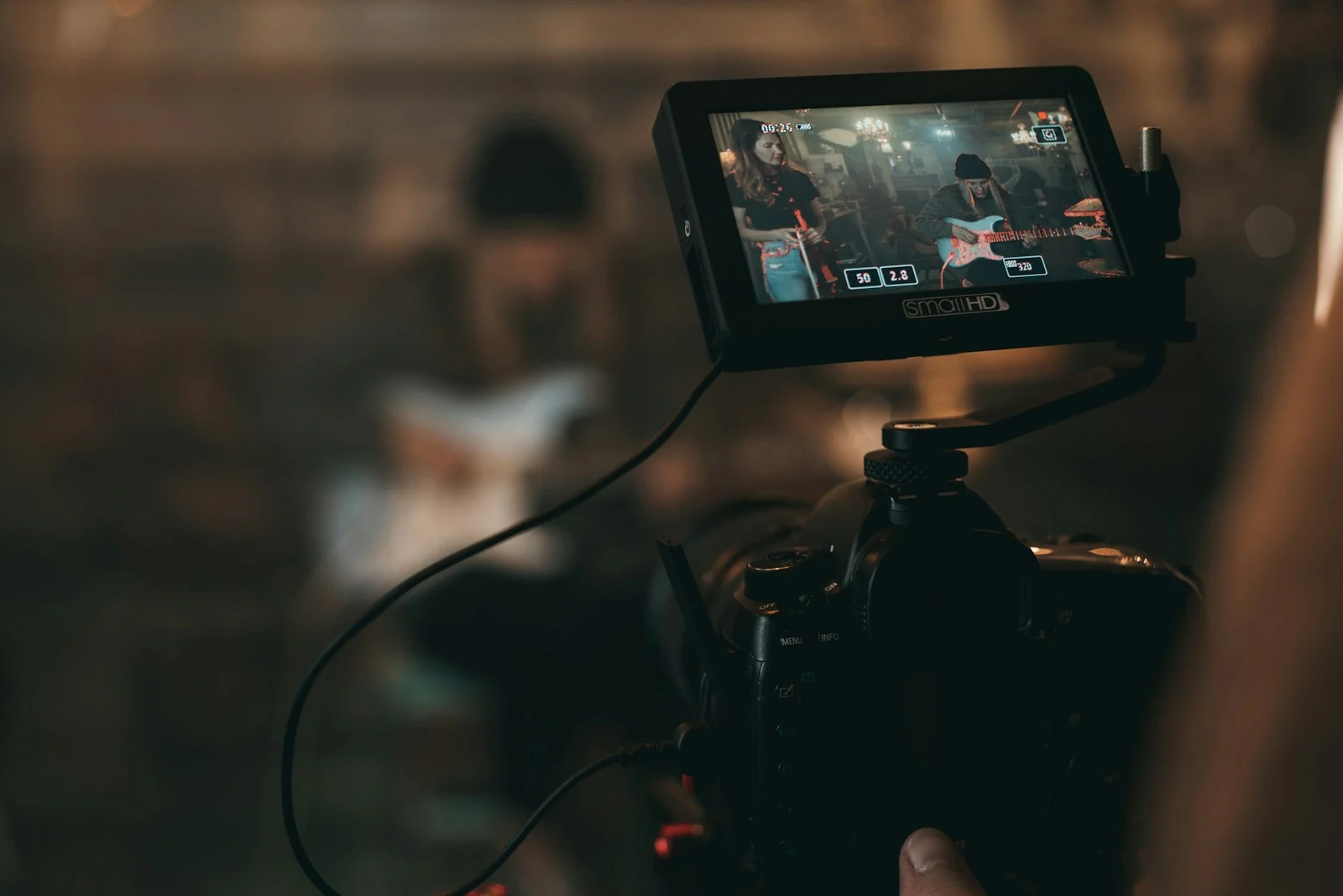 คนถือกล้องถ่ายคลิปผู้หญิงเล่นกีตาร์ ถ่ายคลิปสั้นไว้ลองโพสต์แบบ Trial Reels