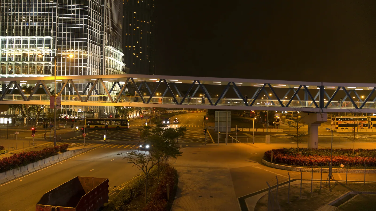 สะพานลอยที่มีคนเดินอยู่ด้านบน ข้ามถนนในเมืองตอนกลางคืน