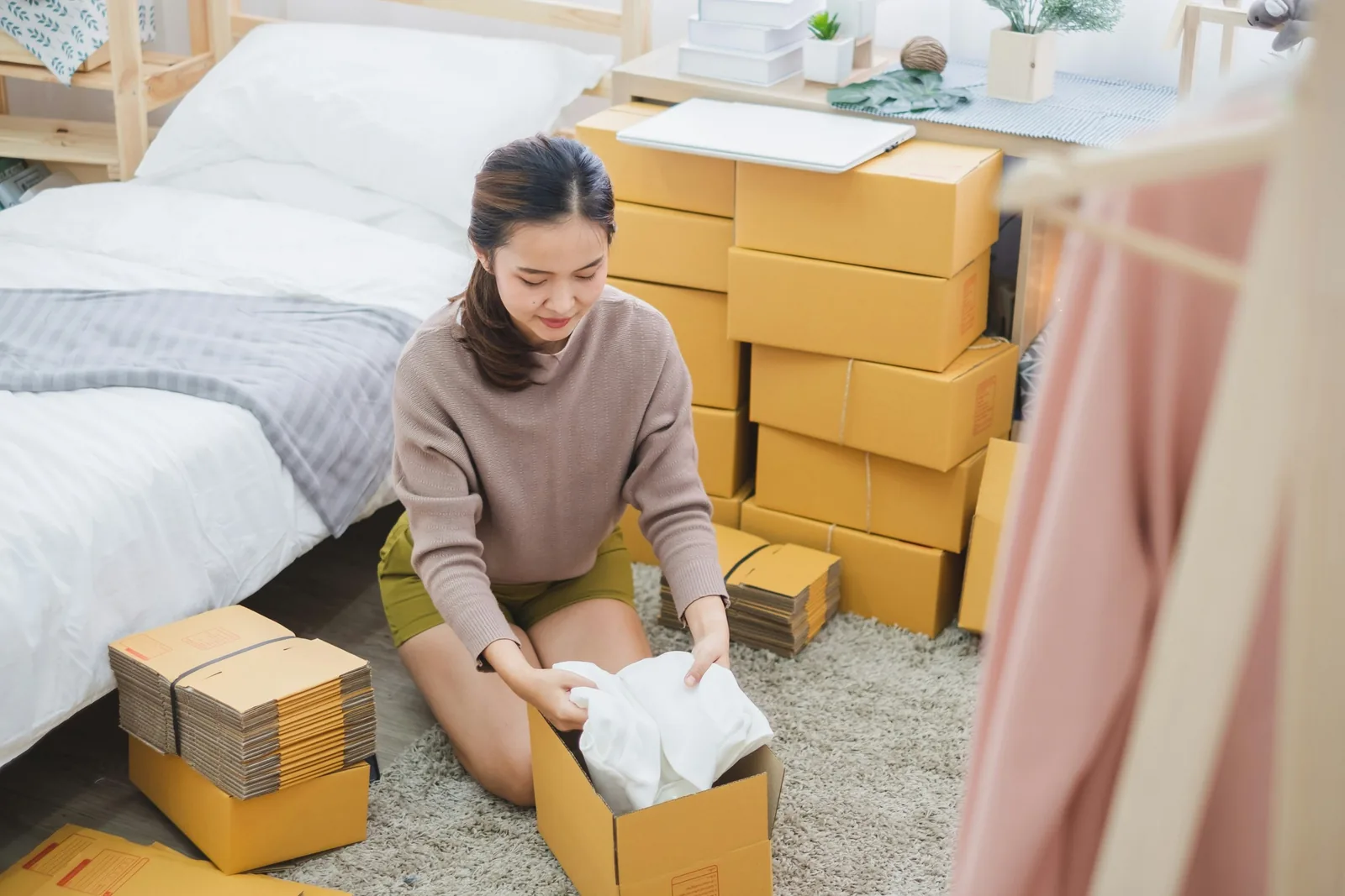 คนขายของออนไลน์พับเสื้อผ้าใส่กล่องพัสดุเตรียมส่งออเดอร์