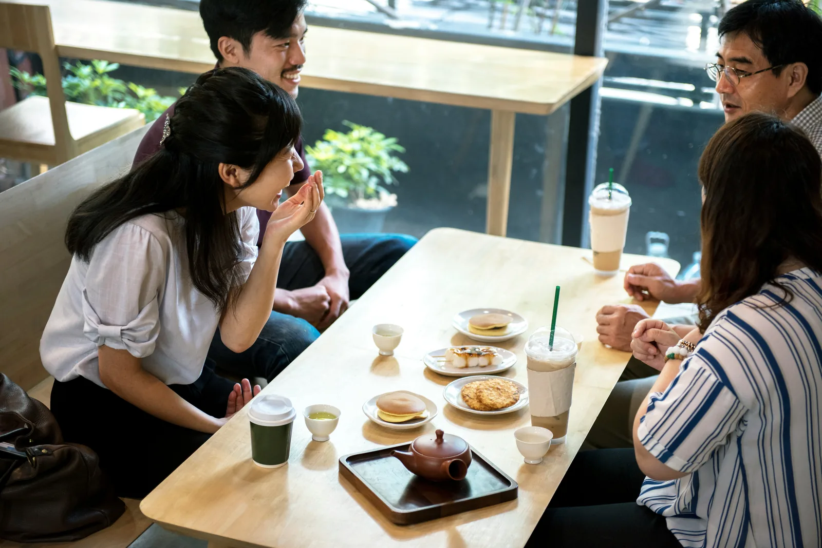 ทีมเล็กนั่งคุยกันรอบโต๊ะในร้าน มีสมุดจดและแก้วกาแฟ