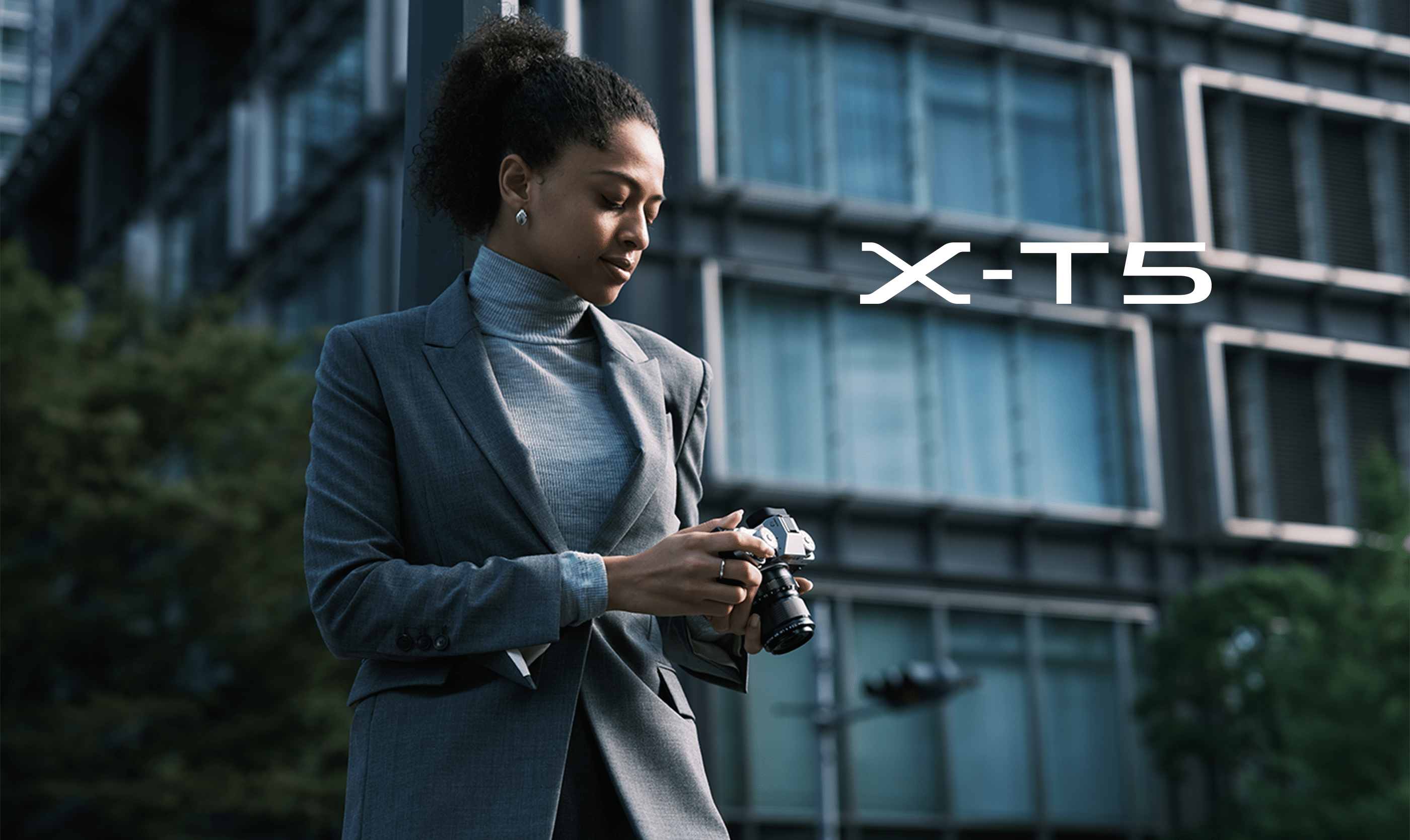 ผู้หญิงถือกล้อง Fujifilm X-T5 สีเงินยืนกลางเมือง ภาพหลักจากหน้าสินค้าทางการ