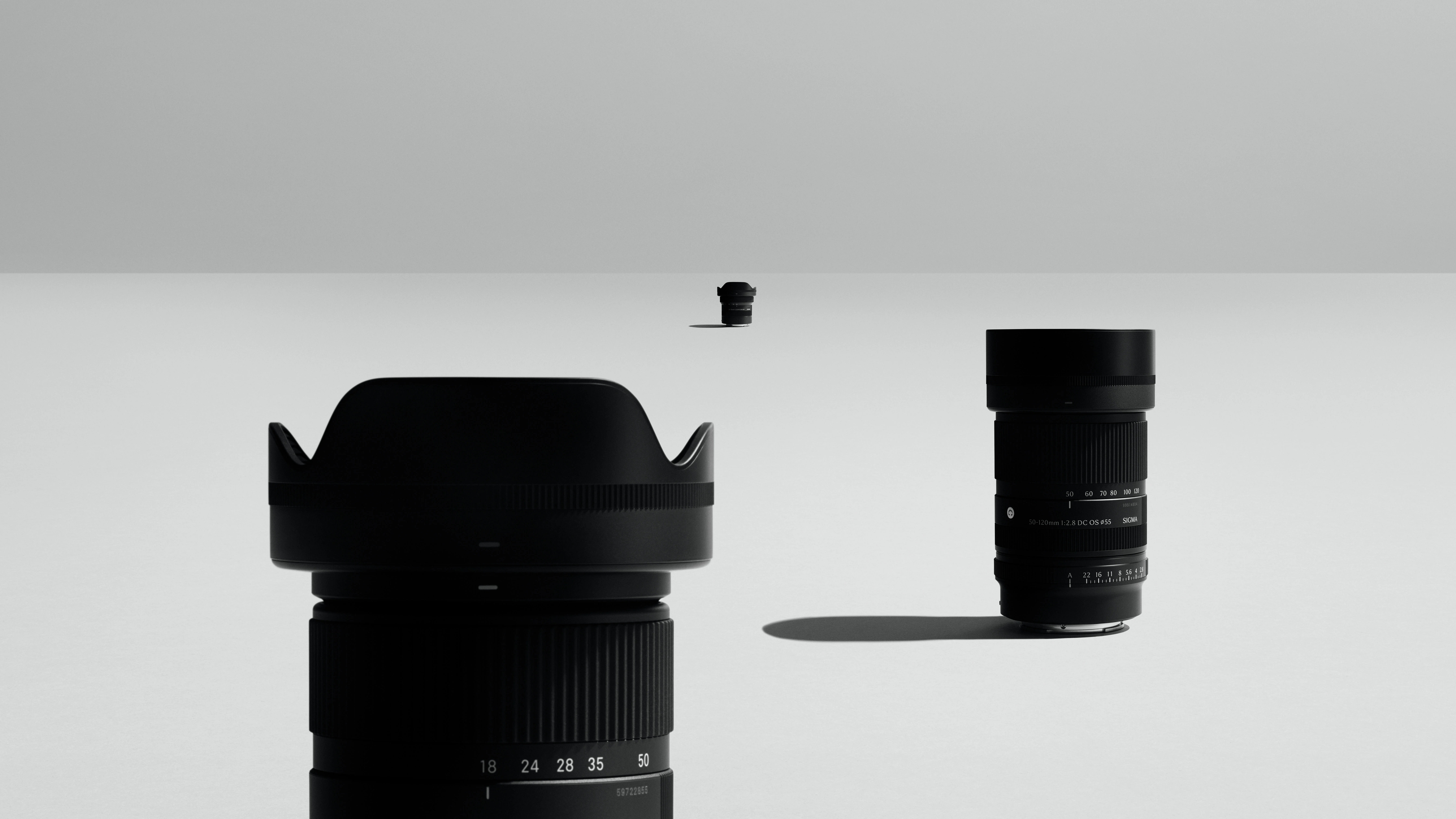 เลนส์ค่ายนอก SIGMA ซีรีส์ DC F2.8 วางบนพื้นสีเทา เลนส์ตัวขวาหันให้เห็นท้ายเมาท์