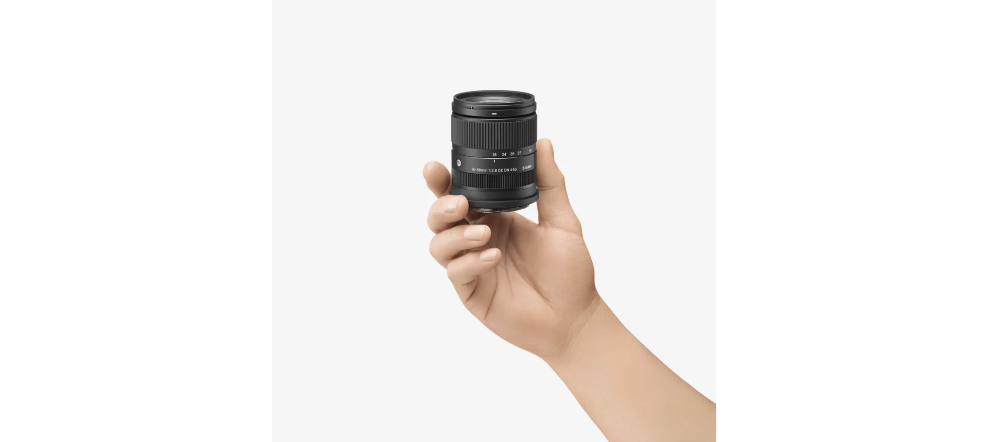 มือถือเลนส์ SIGMA 18-50mm F2.8 DC DN Contemporary ให้เห็นว่าตัวเลนส์เล็กพอดีฝ่ามือ