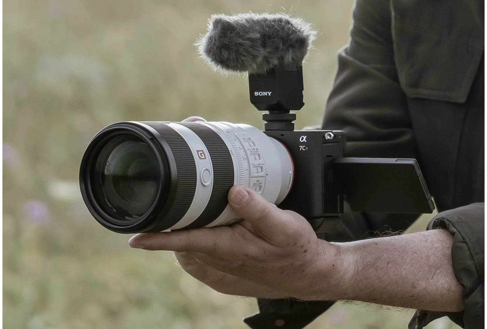 ผู้ชายถือกล้อง Sony α7CR ถ่ายวิดีโอด้วยมือ ใส่เลนส์เทเล