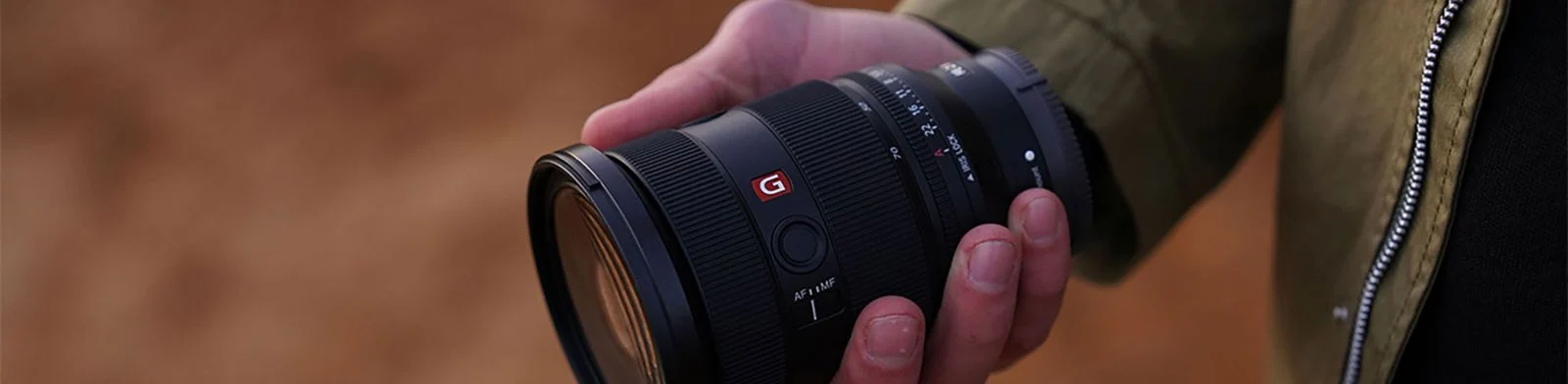 มือขวาถือเลนส์ Sony FE 24-70mm F2.8 GM II หนึ่งในเลนส์ที่รองรับ Breathing Compensation