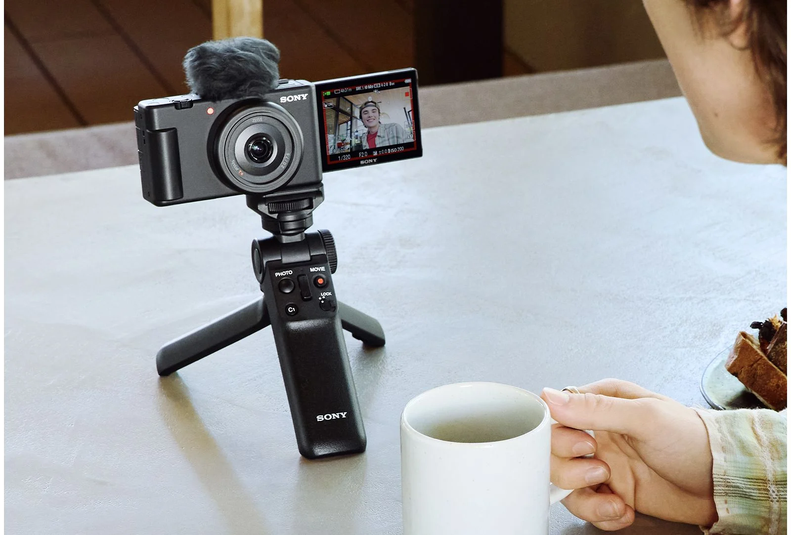 กล้อง Sony ZV-1F รุ่นที่มี Product Showcase ติดด้ามจับตั้งบนโต๊ะข้างแก้วกาแฟ
